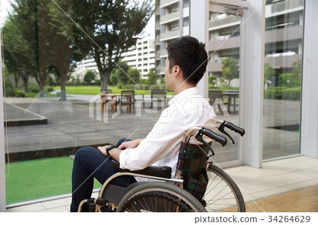 Young man sitting on a wheelchair and looking out 34264629