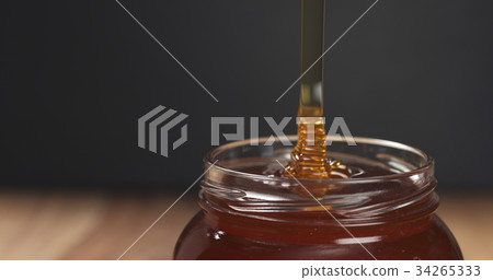 honey drips from dipper in glass jar 34265333