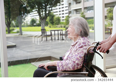Elderly woman talking with care worker while looking at the courtyard 34265444