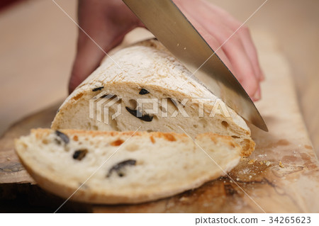 closeup man slicing ciabatta on wood board closeup man slicing ciabatta on wood board 34265623