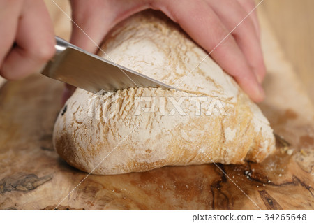 closeup man slicing ciabatta on wood board closeup man slicing ciabatta on wood board 34265648