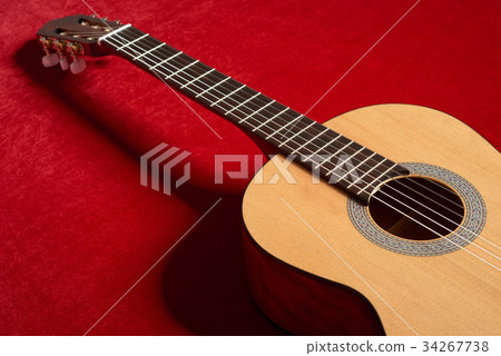 acoustic guitar on red fabric, closeup objects 34267738