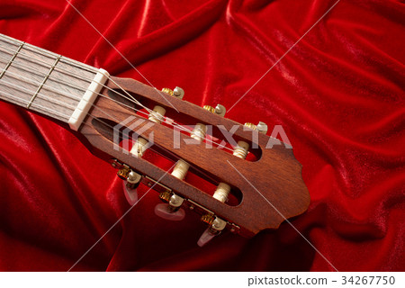 acoustic guitar on red fabric, closeup objects 34267750