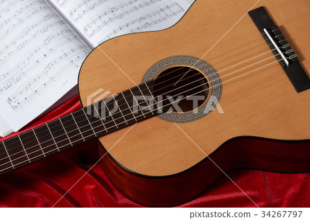 acoustic guitar on red fabric, closeup objects 34267797