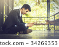A male businessman is playing a mobile phone. 34269353