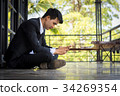 A male businessman is playing a mobile phone. 34269354