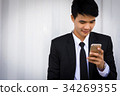 A male businessman is playing a mobile phone. 34269355