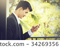 A male businessman is playing a mobile phone. 34269356