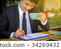 Businessman drinking coffee and reading a report 34269432