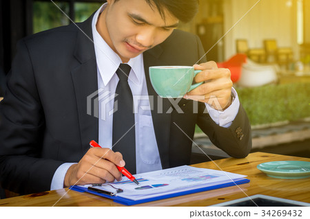 Businessman drinking coffee and reading a report 34269432