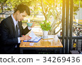 Businessman drinking coffee and reading a report 34269436