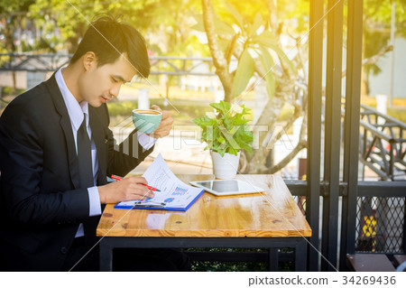 Businessman drinking coffee and reading a report 34269436