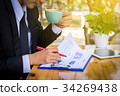 Businessman drinking coffee and reading a report 34269438