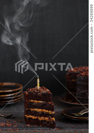 Piece of birthday chocolate cake with blown candle Piece of birthday chocolate cake with blown candle 34269899