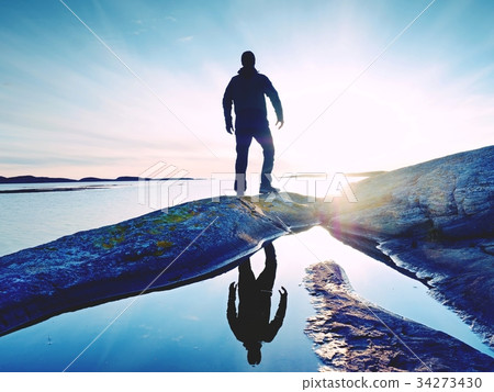 Tall backpacker watch clear sunny sunset over sea 34273430