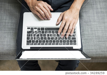 Man uses laptop on sofa in his home. High angle view, Work at h Man uses laptop on sofa in his home. High angle view, Work at h 34289259