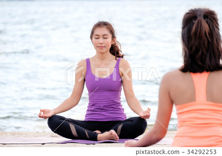 Yoga class at sea beach,Master doing lotus pose Yoga class at sea beach,Master doing lotus pose 34292253