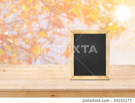 Blackboard on wood table top with blur maple leaf Blackboard on wood table top with blur maple leaf 34292271