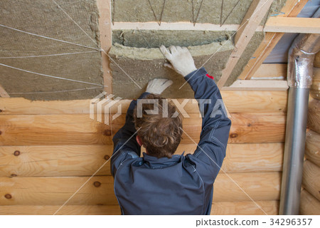 Worker installing insulation panels of mineral Worker installing insulation panels of mineral 34296357