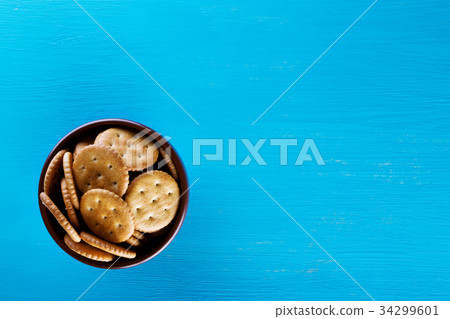 Bowl with crispy crackers on blue background Bowl with crispy crackers on blue background 34299601