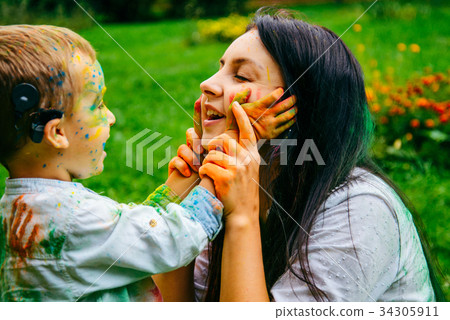 Happy mother and son playing with holi paints Happy mother and son playing with holi paints 34305911