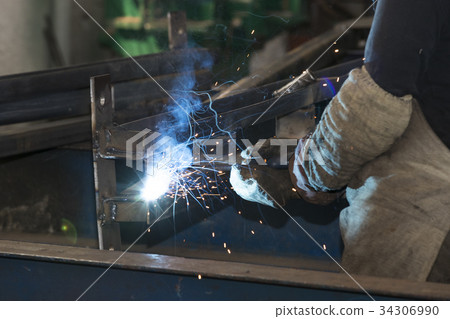 Metalworking shop workers work behind machines and Metalworking shop workers work behind machines and 34306990