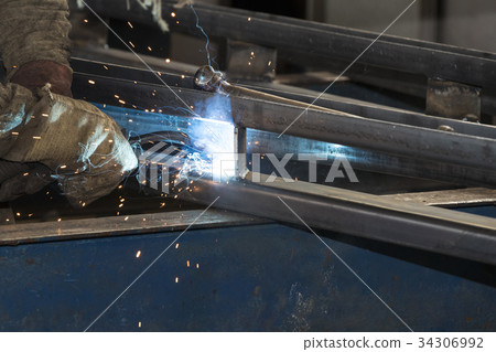 Metalworking shop workers work behind machines and Metalworking shop workers work behind machines and 34306992