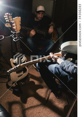Guitarists rehearsing in dark music studio Guitarists rehearsing in dark music studio 34308283