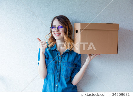 woman in jeans shirt standing on white wall woman in jeans shirt standing on white wall 34309681