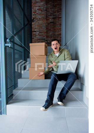 Handsome man with moving boxes and laptop Handsome man with moving boxes and laptop 34309754