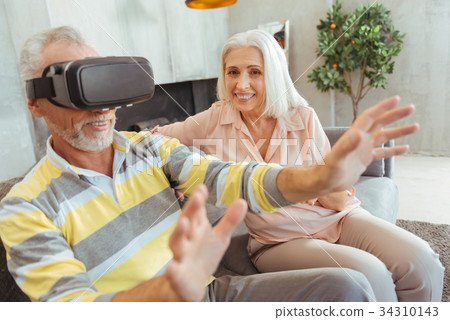 Positive retired man wearing VR glasses at home 34310143