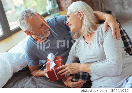 Positive aged loving couple holding a present 34311012