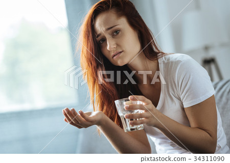 Sad pretty woman taking medication Sad pretty woman taking medication 34311090
