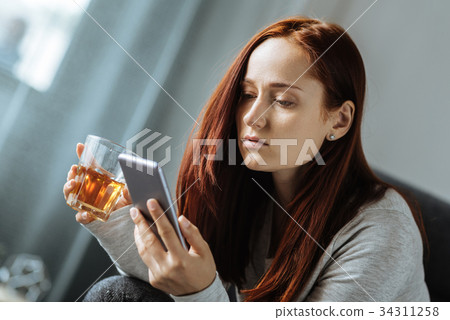 Pleasant sad woman holding a glass of whisky 34311258