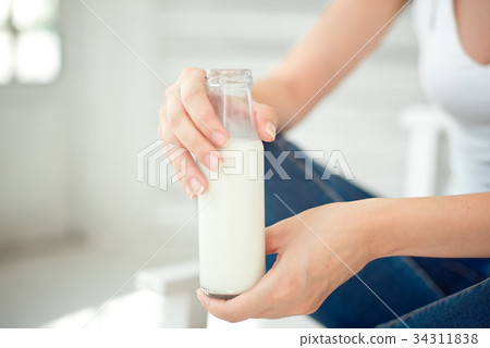 Young woman holding a bottle of milk in her hand Young woman holding a bottle of milk in her hand 34311838