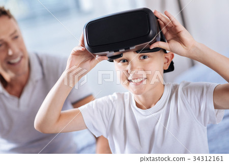 Happy excited boy removing VR headset after 34312161