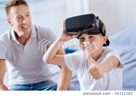 Joyful boy in VR headset showing thumbs up 34312162