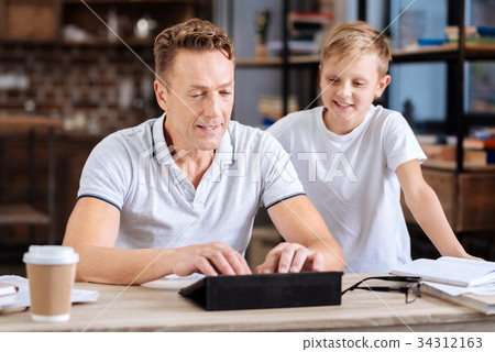 Smiling boy watching father type on tablet 34312163