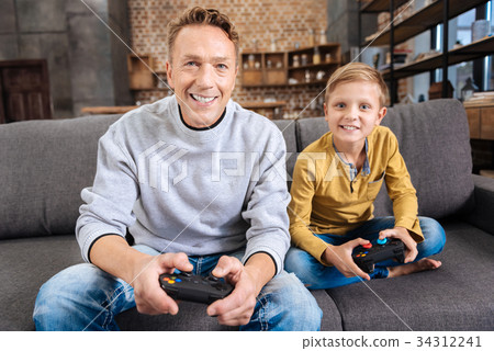 Cheerful father and son playing video game console 34312241