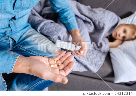 Caring father holding pills for his ill son 34312314