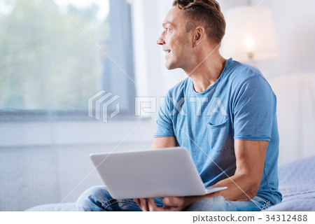 Cheerful man holding laptop and looking into the 34312488