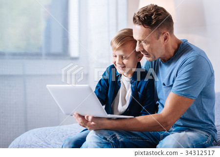 Caring father watching cartoons with his son on 34312517