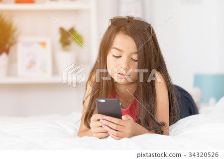 Happy asian girl reading smart phone with smile face on bed . Happy asian girl reading smart phone with smile face on bed . 34320526