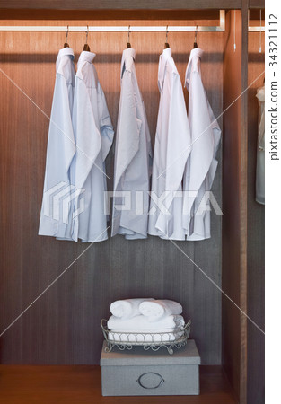 row of white shirts hanging in wooden wardrobe row of white shirts hanging in wooden wardrobe 34321112