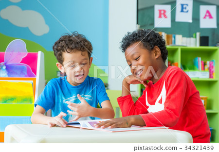Two boy kid sit on table and reading tale book 34321439