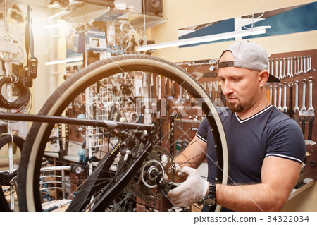 Mechanic repairing a mountain bike in a workshop 34322034