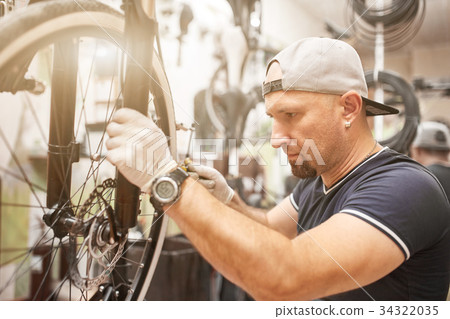 Mechanic repairing a mountain bike in a workshop Mechanic repairing a mountain bike in a workshop 34322035
