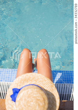 Beautiful girl in a hat near a blue pool - sun 34332789