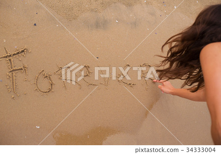 The girl is writing an inscription on the sand 34333004