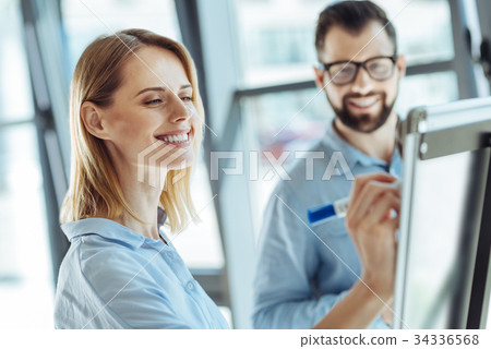 Smiling woman writing on a whiteboard in office Smiling woman writing on a whiteboard in office 34336568